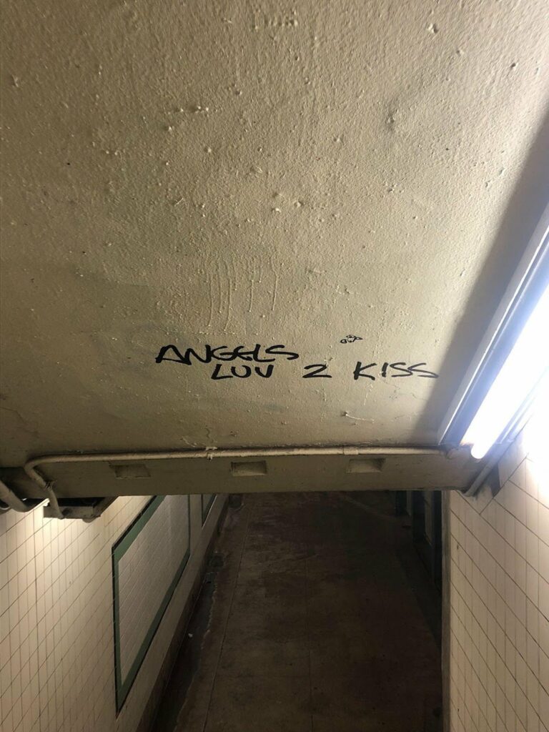 Photo taken while entering the Clinton-Washington G train subway station. On the roof above the staircase is the tag 'Angels Luv 2 Kiss' written in black sharpie.