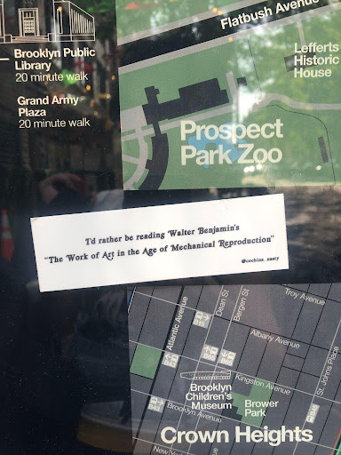 Picture of a sticker plastered over a map of Crown Heights and Prospect Park. The sticker reads 'I'd rather be reading Walter Benjamin's the work of art in the age of mechanical reproduction'