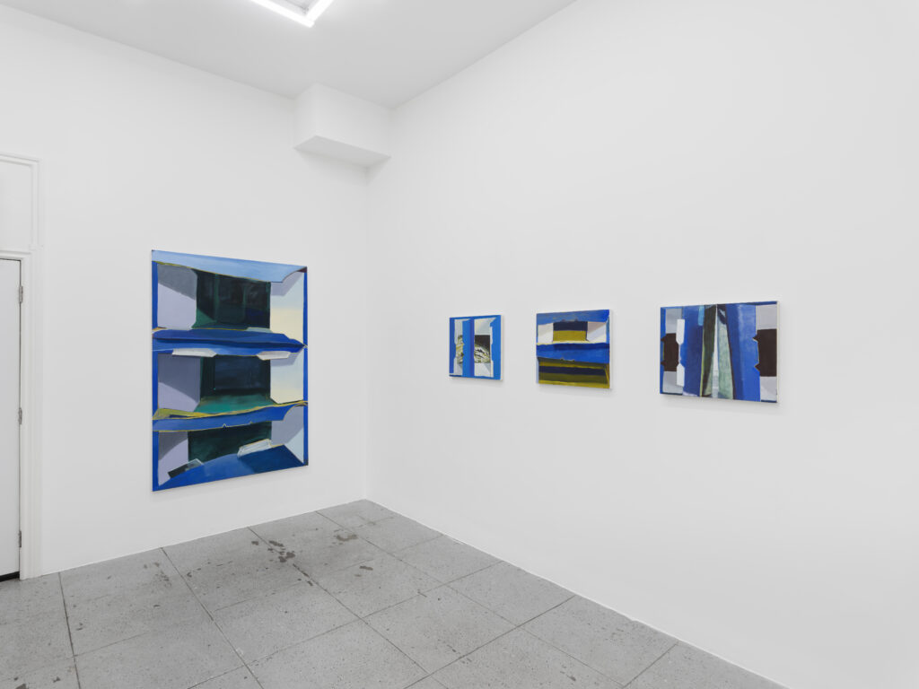 an exhibition installation view of four paintings depicting still life paintings of blue Pop Secret popcorn boxes. One large painting hangs on one wall, and three small paintings hang on the other wall